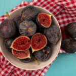 top-view-sweet-ripe-black-mission-figs-bowl-red-checked-cloth-blue-wooden-wall-1.jpg